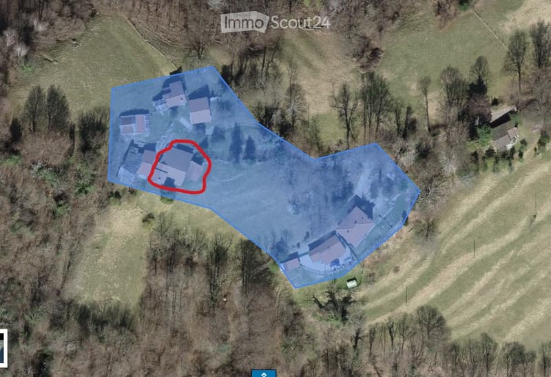 Aerial view of a rural property with multiple buildings, including a main house and outbuildings, surrounded by open land and trees.
