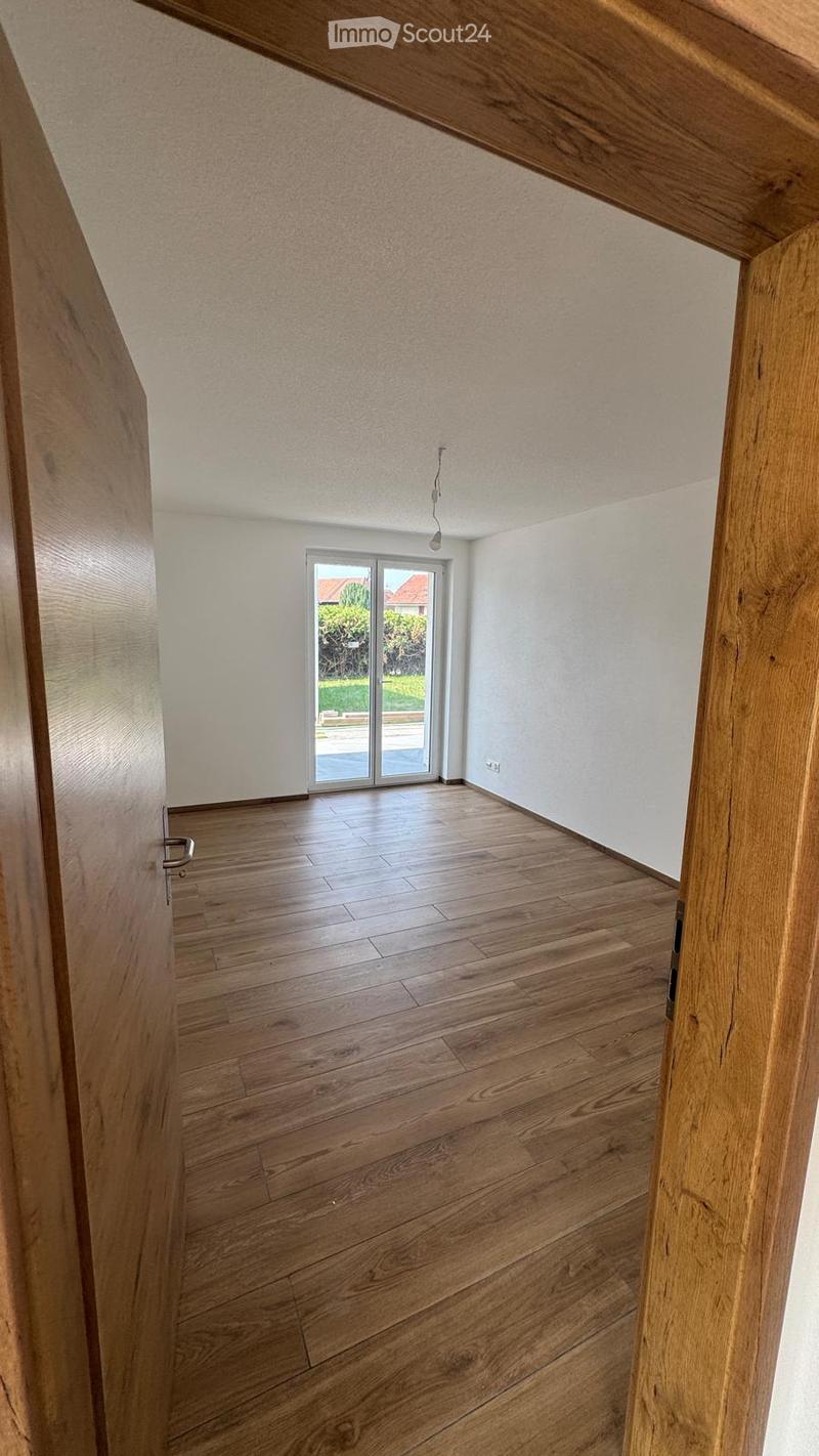 Empty room with wooden flooring, white walls, and a large sliding glass door leading to an outdoor area.