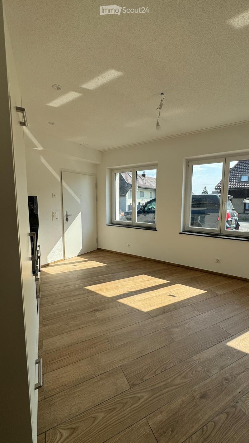 Empty room with wooden flooring, white walls, and large windows letting in natural light. No furniture or equipment present.