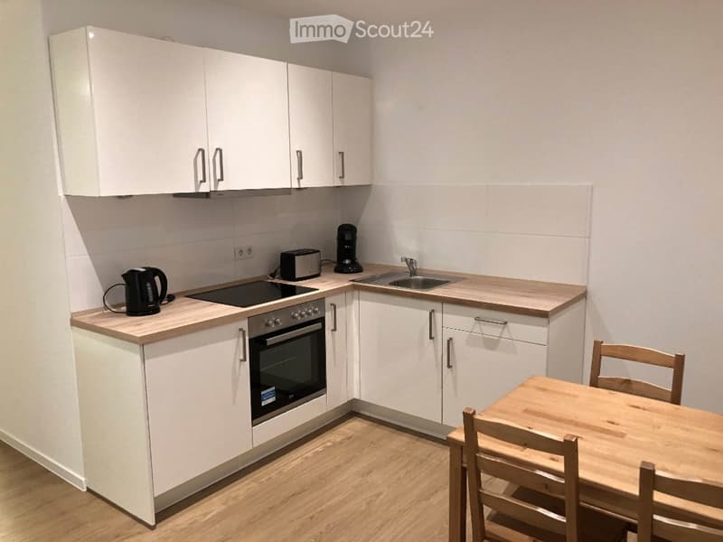 Modern kitchen with white cabinets, wooden countertops, and a small dining area with a wooden table and chairs.