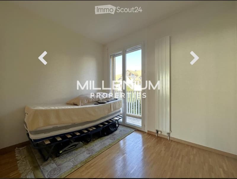 Bright bedroom with wooden flooring, a single bed, a radiator, and a rug. Large sliding glass doors lead to a balcony.