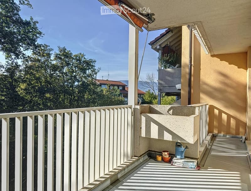 Balcony with white railing, concrete planter, and small potted plants.