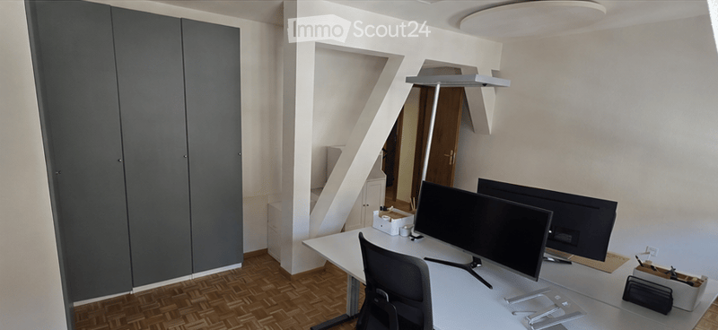Modern, minimalist office space with a white desk, ergonomic chair, dual computer monitors, sleek grey cabinet, and a large mirror on the wall.