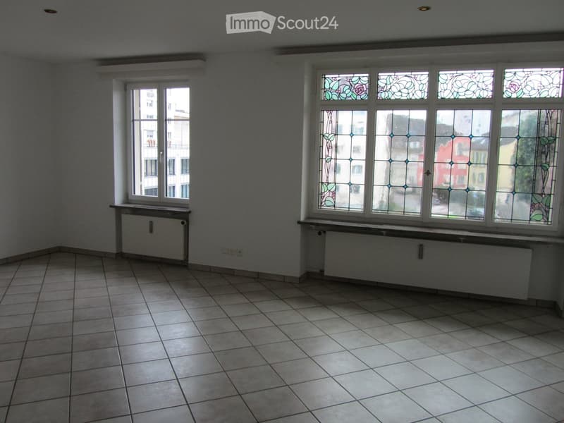 Empty room with white walls, tiled floor, and two large windows with stained glass.