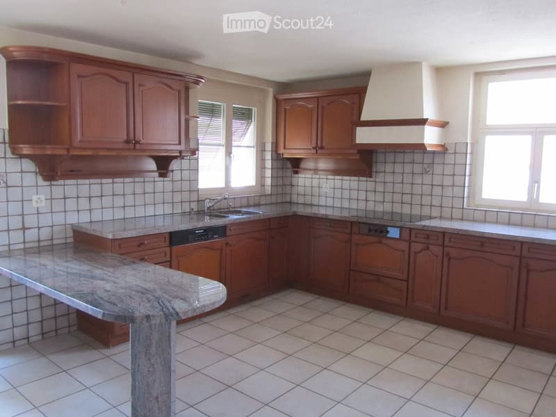 Modern kitchen with wooden cabinets, granite countertops, and tiled flooring.