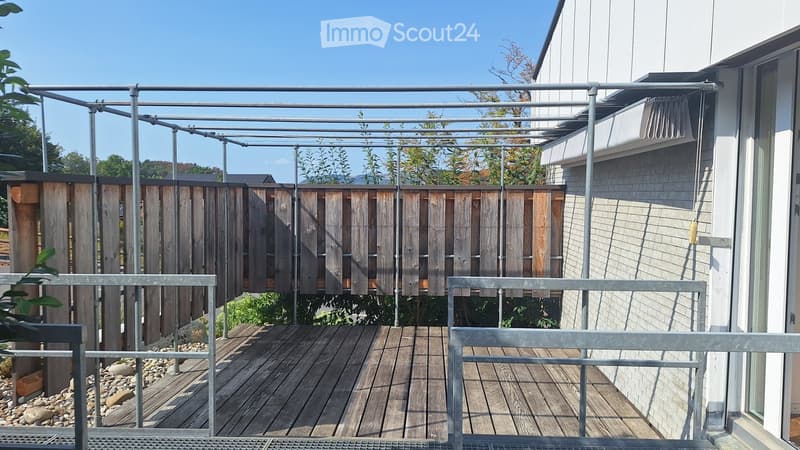 Wooden deck with metal railings, wooden privacy screens, and a clear blue sky background.