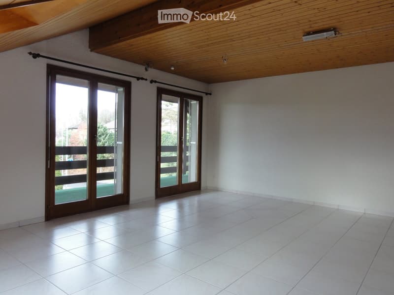 Empty room with white tiled flooring, white walls, and large sliding glass doors leading to an outdoor area.