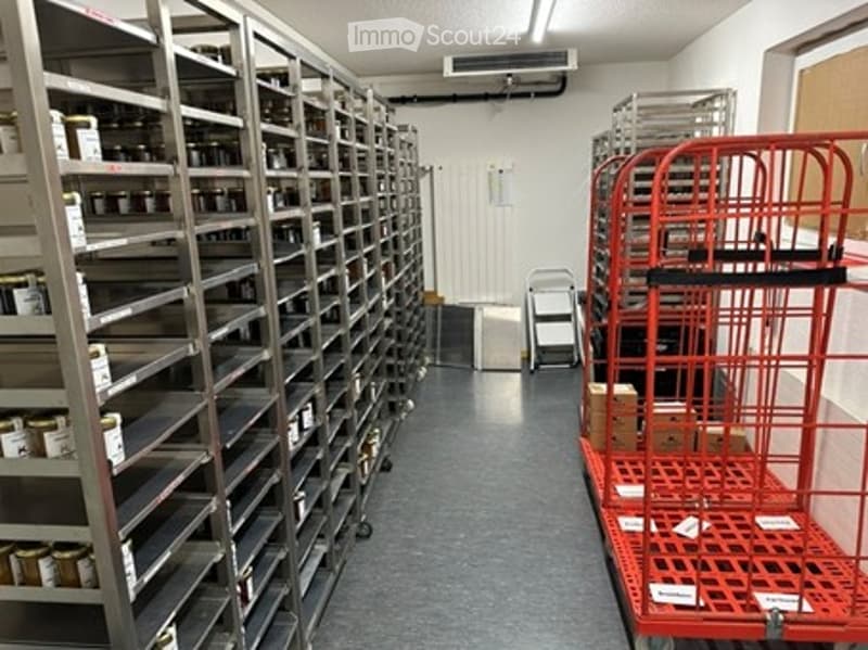 Storage area with metal shelving units filled with various items, red carts, and boxes on the floor.