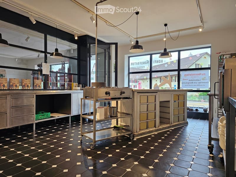 Modern kitchen with stainless steel oven, wooden cabinets, pendant lights, and a cart with containers.