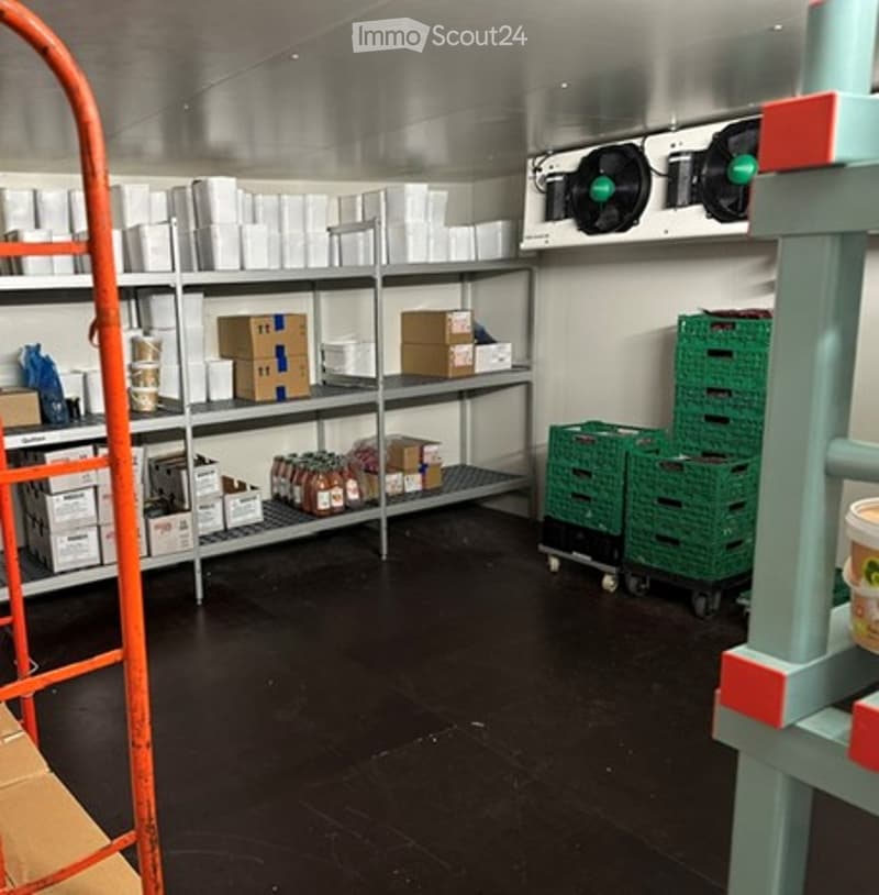 Empty storage room with metal shelving, boxes, and green crates. No furniture or equipment.