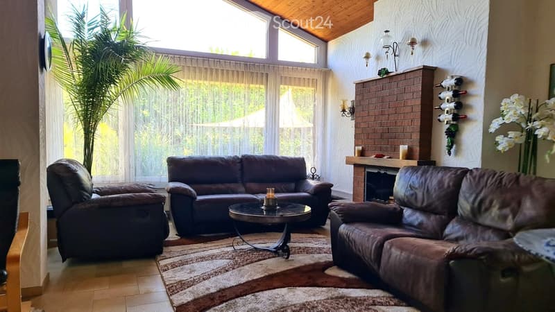 Cozy living room with dark leather sofas, a coffee table, fireplace, wine rack, and decorative candles.
