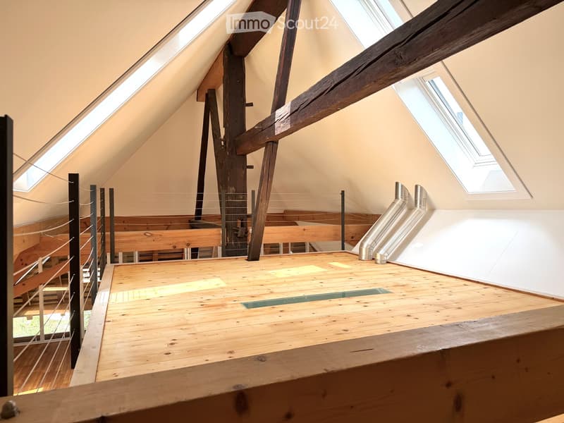 Open loft space with wooden flooring, exposed wooden beams, skylights, and metal ductwork. No furniture or furnishings present.