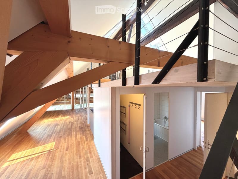 Open hallway with wooden flooring, white walls, and visible rooms including a bathroom with a bathtub and a closet with hanging space.