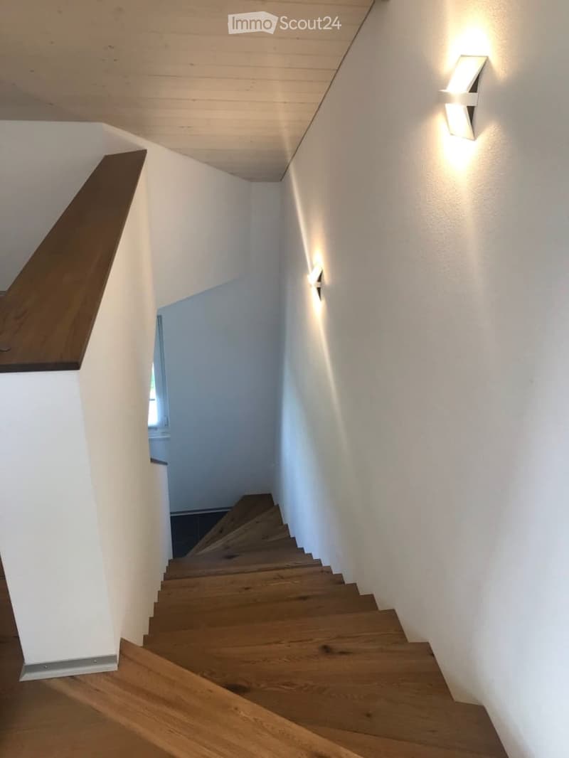 Wooden staircase with white walls and modern wall-mounted lighting fixtures.