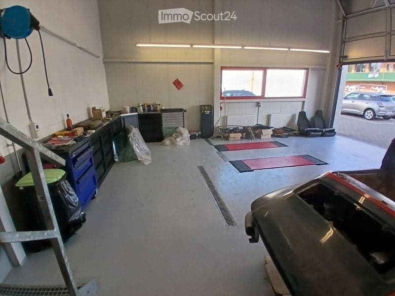 {"visible_features": ["Garage"], "type": "Garage", "objects": [], "description": "Garage with workbenches, tools, and a car partially visible. The space includes a large open door leading outside, with a few cars visible in the background.", "localized_de
