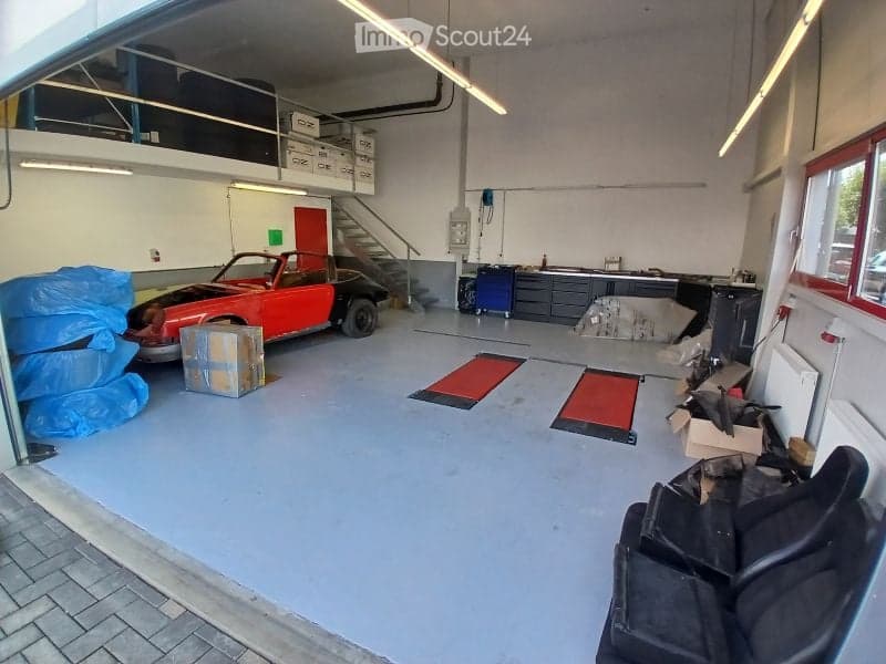 {"visible_features": ["Garage"], "type": "Garage", "objects": [], "description": "Clean, spacious garage with a red convertible car, workbenches, storage boxes, and a staircase leading to an upper level.", "localized_descriptions": {"EN": "Clean, spacious