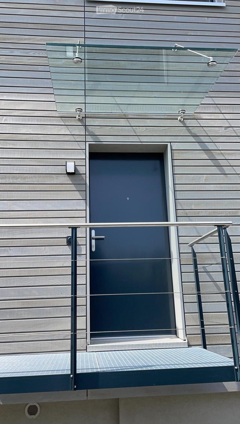 Glass railing balcony, gray wall, glass canopy, security camera, black door with a silver handle