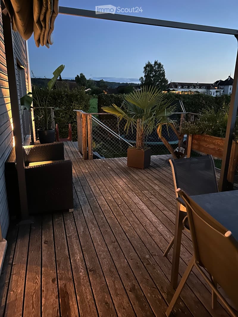 wooden deck with chairs and table, potted plants, railings, beautiful view of the countryside