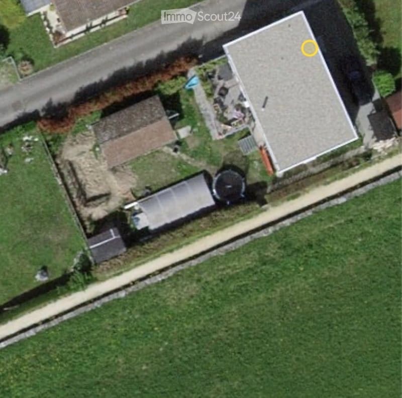 Aerial view of a residential property with a swimming pool, patio area, and surrounding greenery.