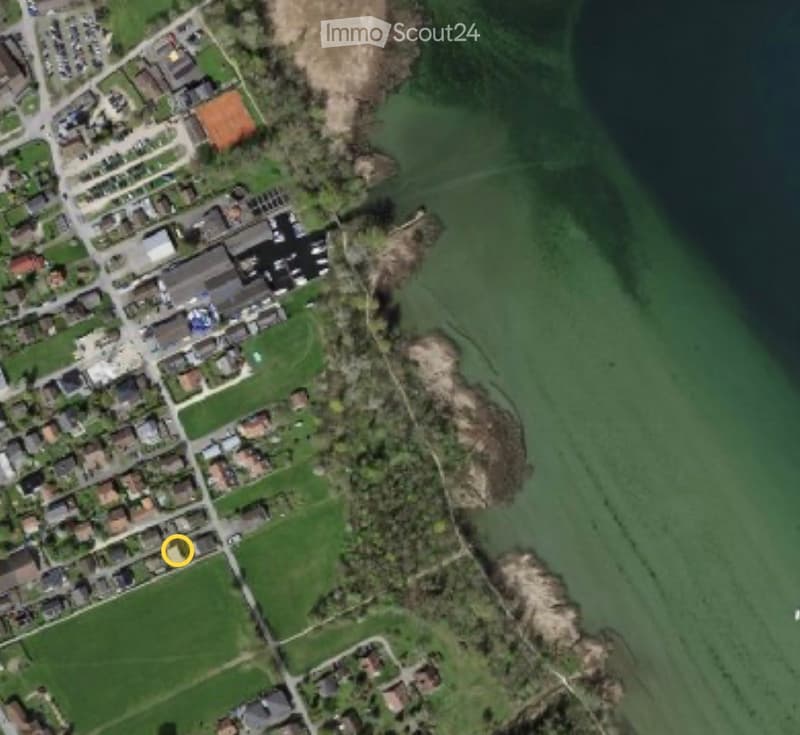 Aerial view of a residential area with houses, parking lots, and green spaces.