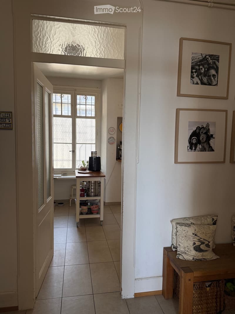 Hallway with a wooden bench, decorative pillows, a small table with a plant, and framed pictures on the wall.