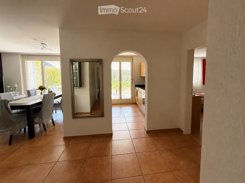 Bright dining area with tiled floor, large mirror, and access to a kitchen and outdoor space.