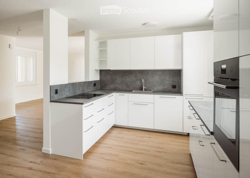 Modern kitchen with white cabinets, dark countertops, and stainless steel appliances.