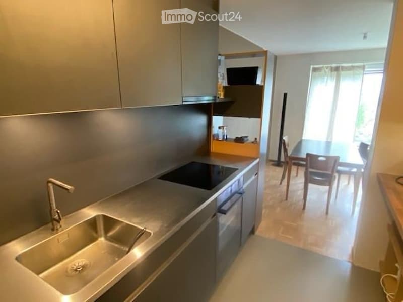 Modern kitchen with stainless steel sink, faucet, stove, and cabinets. Adjacent dining area with a table and chairs.