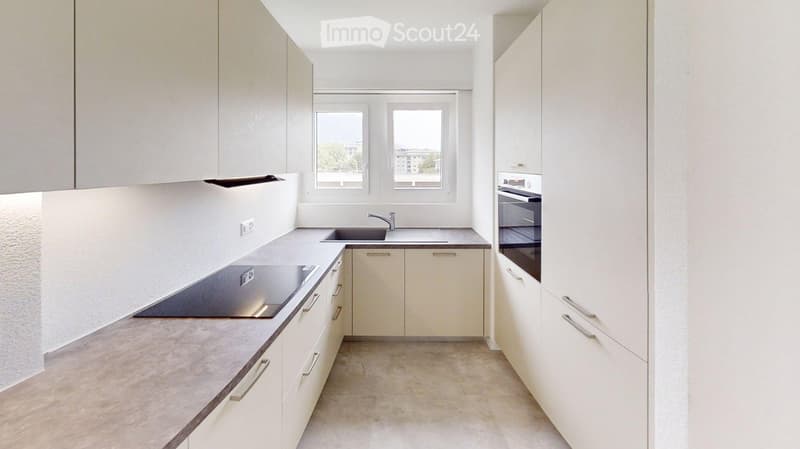 Modern kitchen with white cabinets, a sink, a faucet, an oven, and a countertop.
