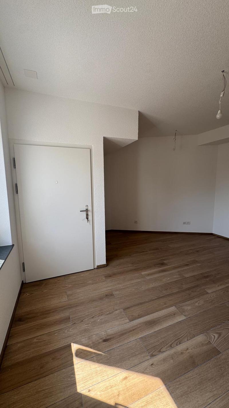 Empty room with wooden flooring, white walls, and a white door. No furniture or equipment visible.