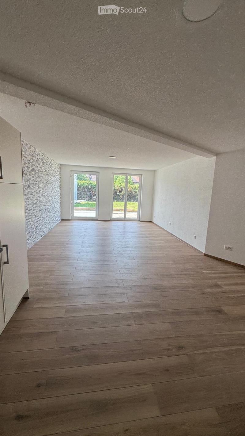 Empty room with wooden flooring, white walls, and large sliding glass doors leading to an outdoor area.