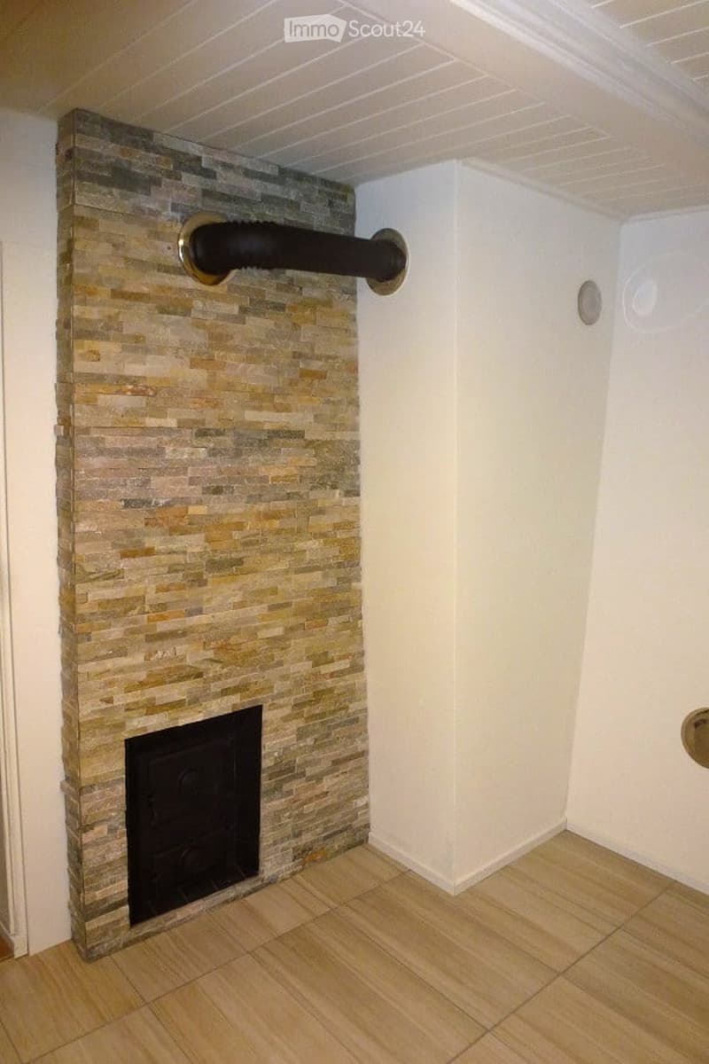 A modern bathroom with a stone-tiled wall, a built-in fireplace, and a sleek black pipe running horizontally across the wall.
