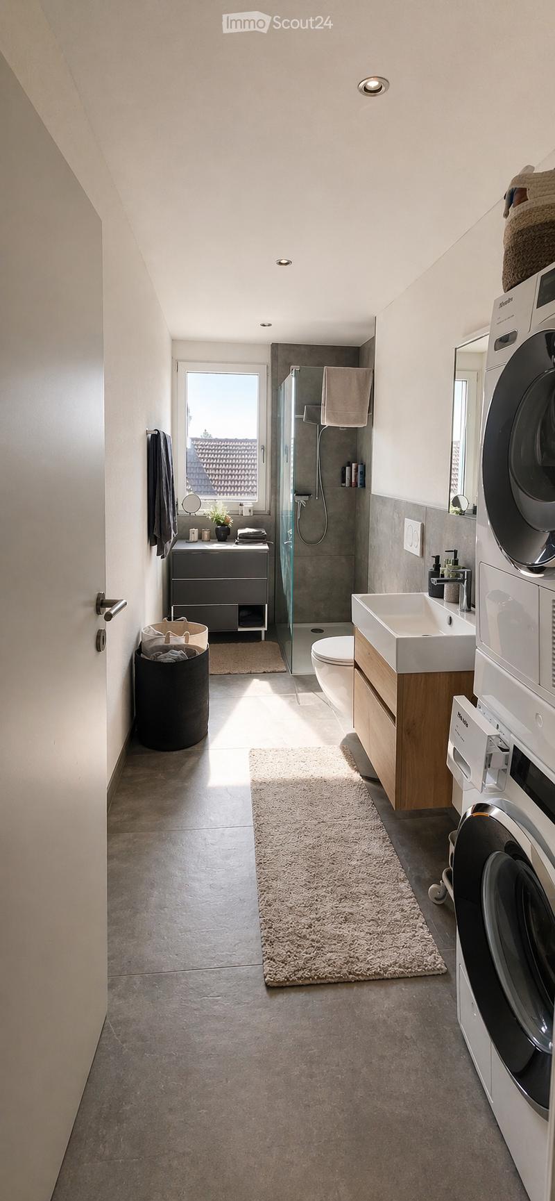 modern bathroom with shower, toilet, sink, washing machine, rug, cabinet, mirror, window
