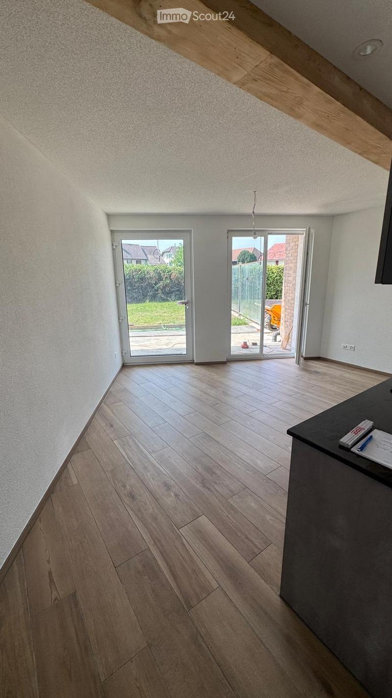Empty room with wooden flooring, white walls, and large sliding glass doors leading to an outdoor area.