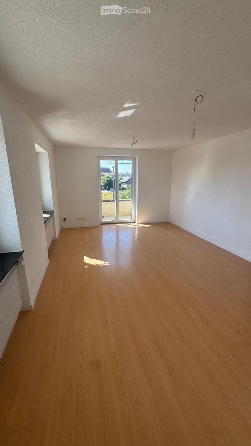 Empty room with wooden flooring, white walls, and large sliding glass doors leading to a balcony.