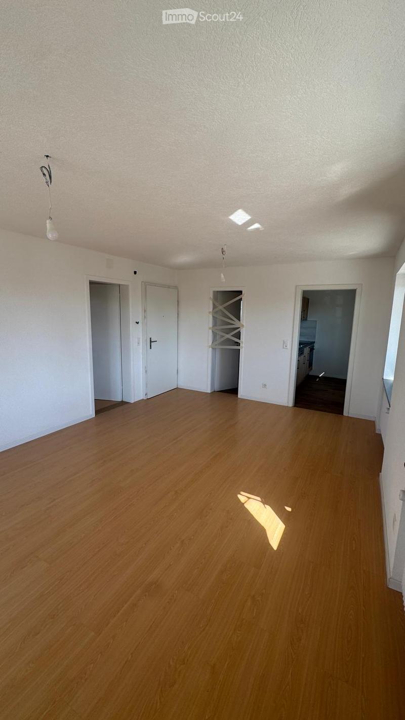 Empty room with light wooden flooring, white walls, and multiple doors leading to other spaces.