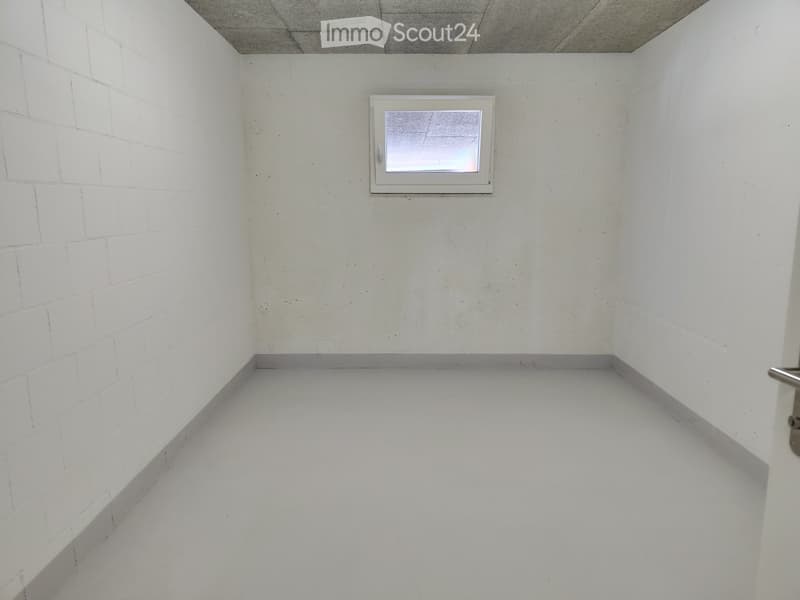 Completely empty room with white brick walls, white concrete floor, and a small window with a white frame.
