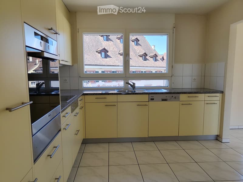 Modern kitchen with light-colored cabinets, stainless steel appliances, and a granite countertop.