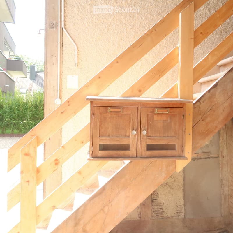 Wooden staircase with a wooden mailbox mounted on the wall above the stairs