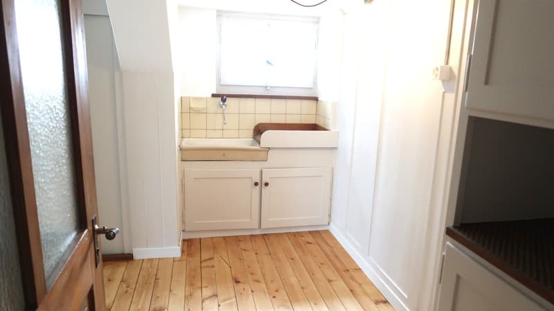 Bathroom with wooden flooring, white cabinets, a sink, and a window above the sink.