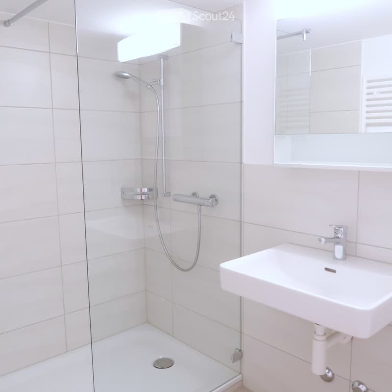 Bathroom with walk-in shower, sink, mirror, tiled walls and floor, shower head, shower arm, faucet, tiled shower tray, drain