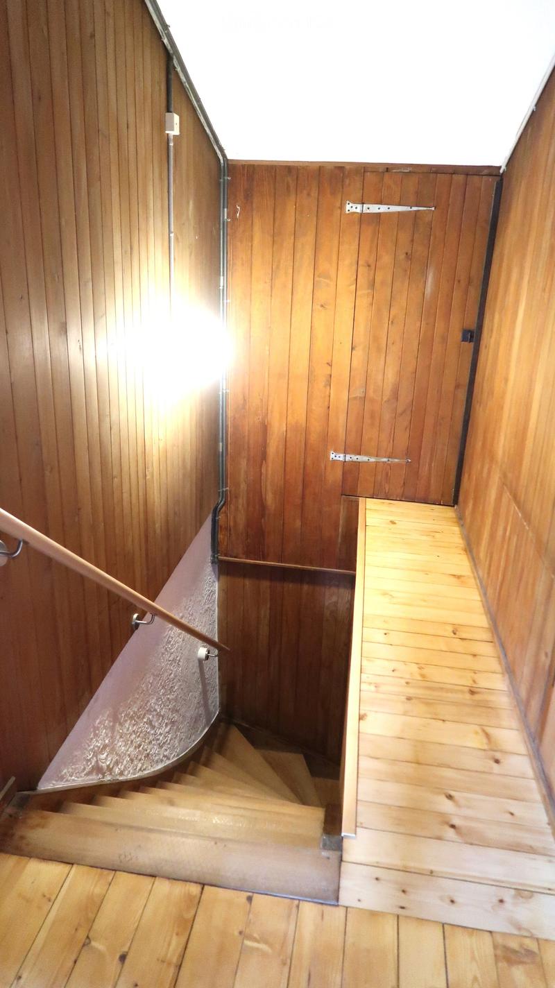 Wooden staircase with a handrail, wooden walls, and a small landing area.