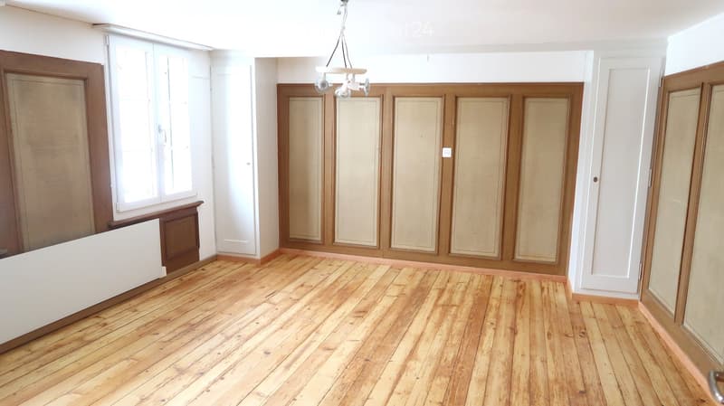 Empty room with wooden flooring, white walls, and large windows. No furniture or equipment present.