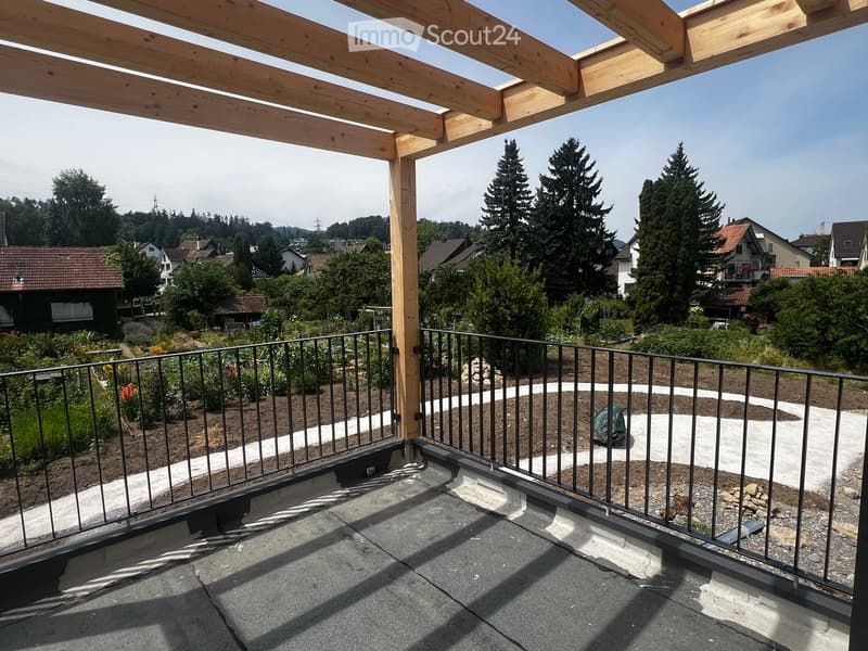 Roof terrace with wooden pergola, metal railing, and view of garden and surrounding houses.