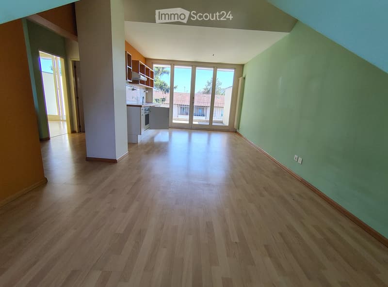 Empty room with wooden flooring, green walls, and large sliding glass doors leading to a balcony.