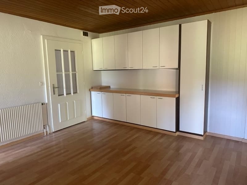 Empty kitchen with white cabinets, wooden countertops, and wooden flooring. No furniture or appliances are present.
