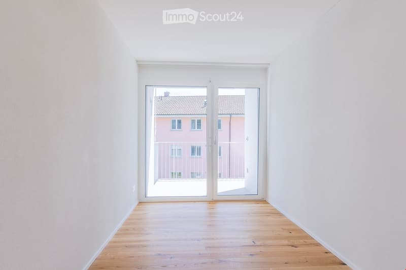 empty room with white walls, wooden floor, sliding doors, and balcony