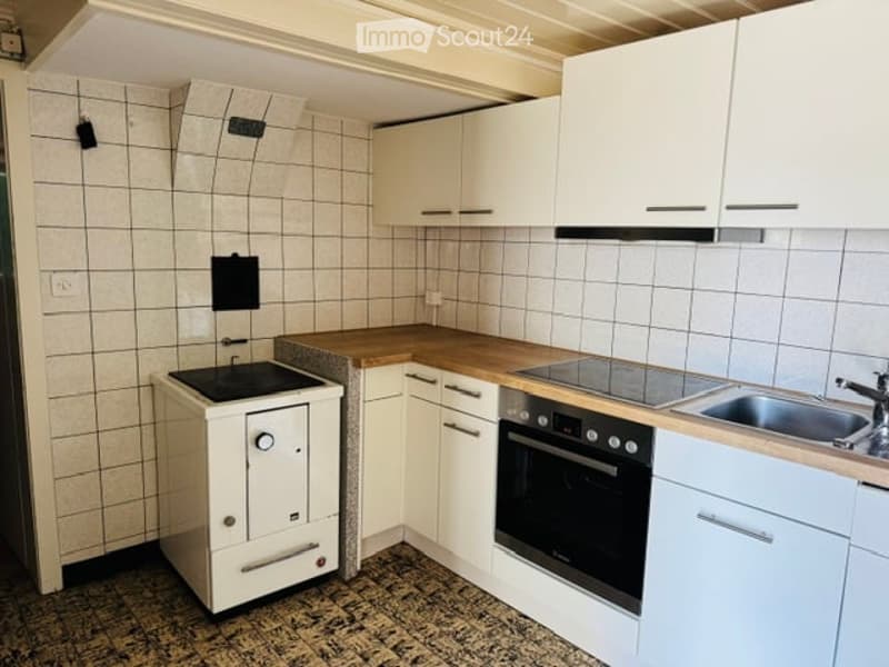 Modern kitchen with white cabinets, wooden countertops, and stainless steel appliances including a stove, oven, and sink.