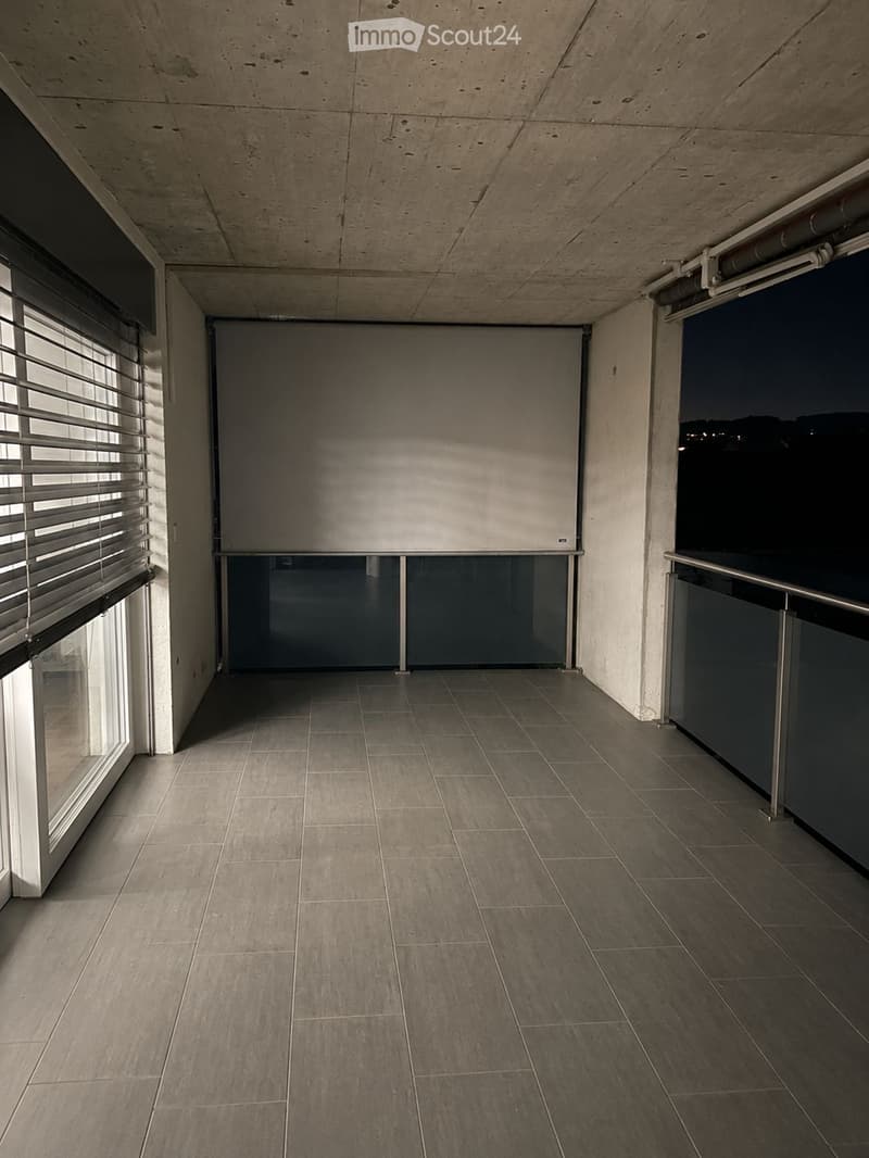 Empty balcony with tiled floor, large windows, and a view of the night sky.