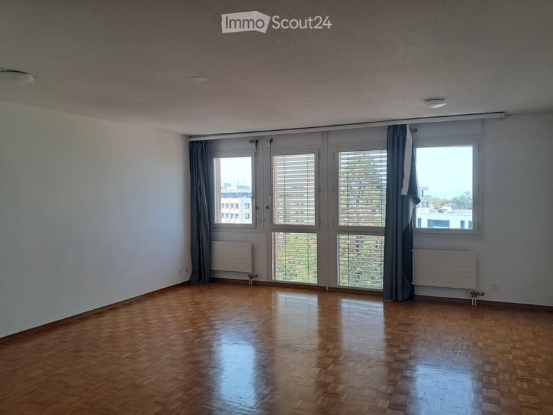 Empty room with wooden flooring, large windows with blinds, and radiators on both sides.